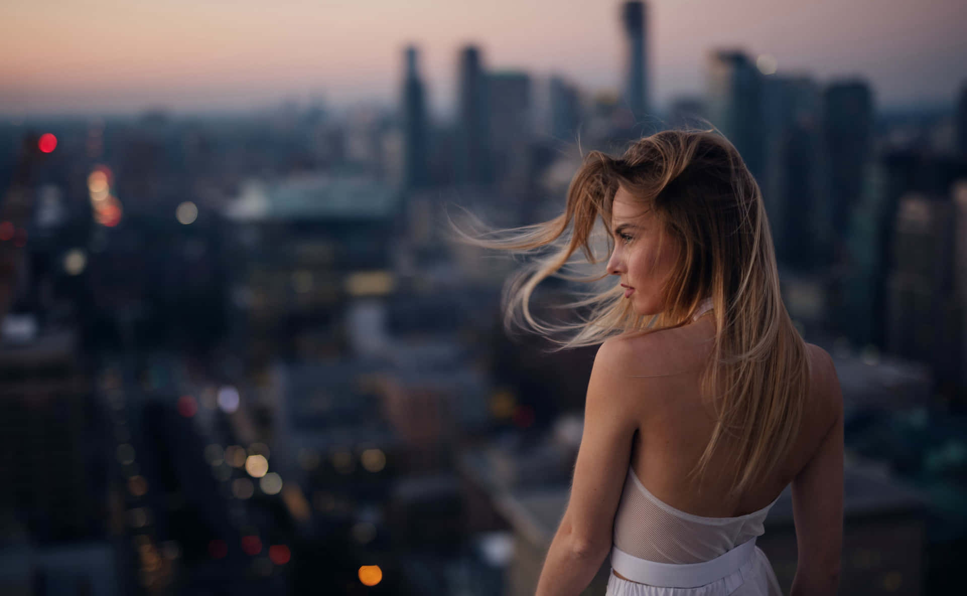 A Woman Is Standing On A Rooftop Overlooking A City