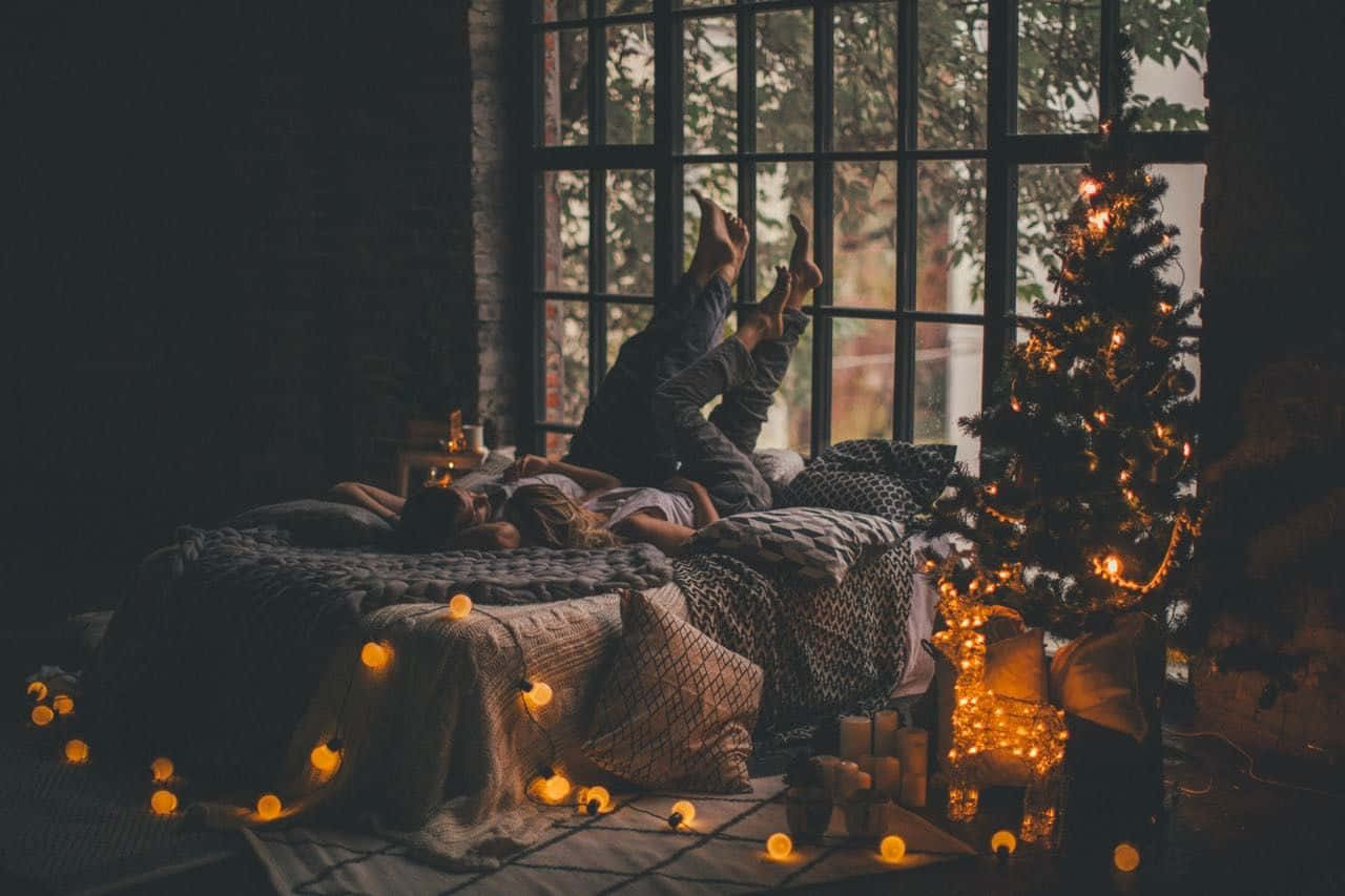 A Woman Laying On A Bed With Christmas Lights Background