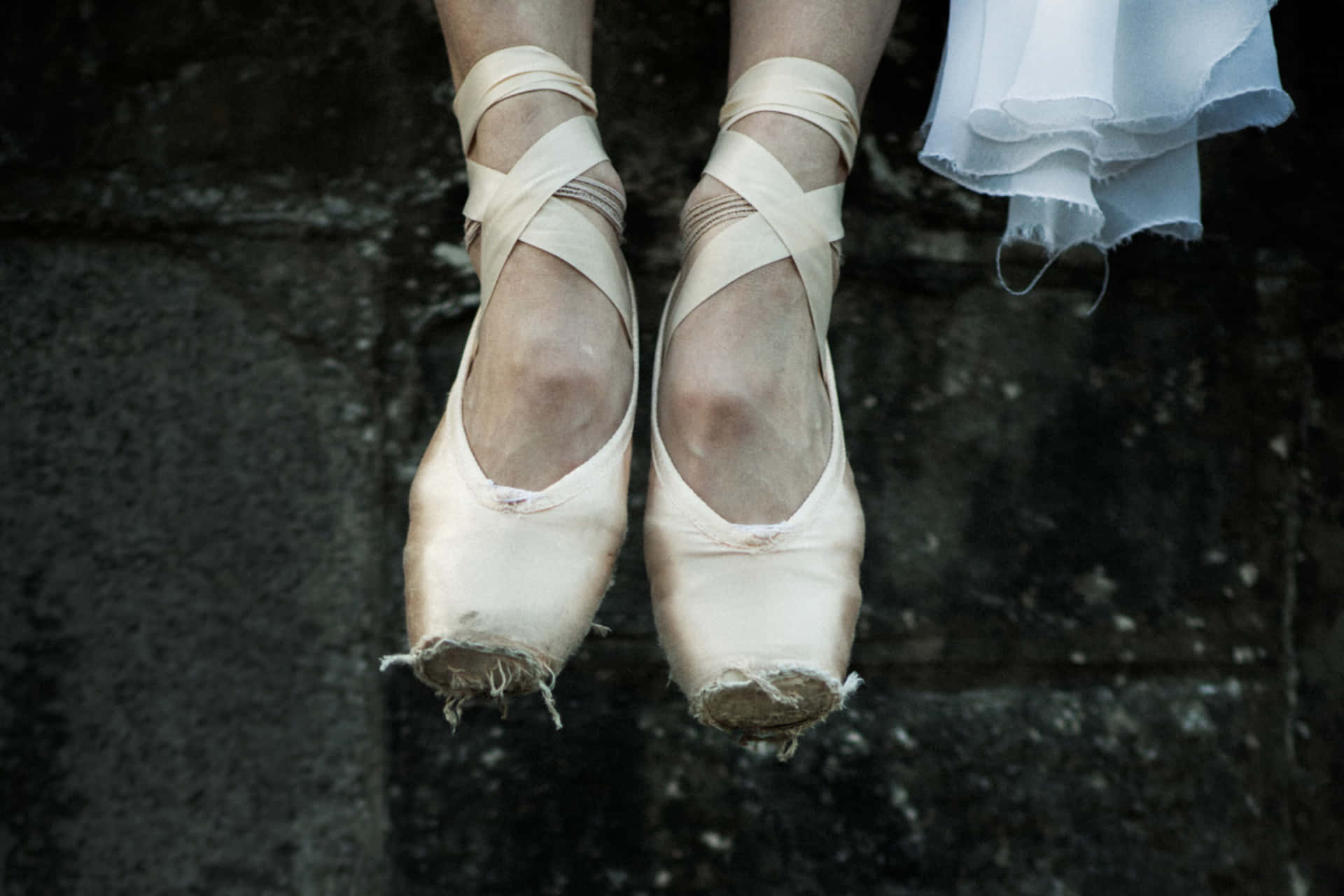 A Woman's Feet Are Hanging From A Wall Background