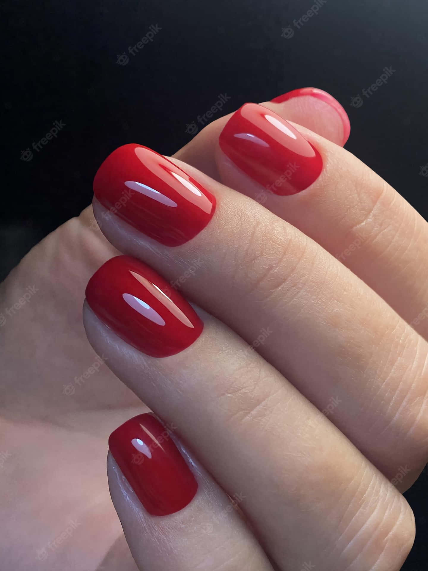 A Woman's Hand Holding A Red Nail Polish Background