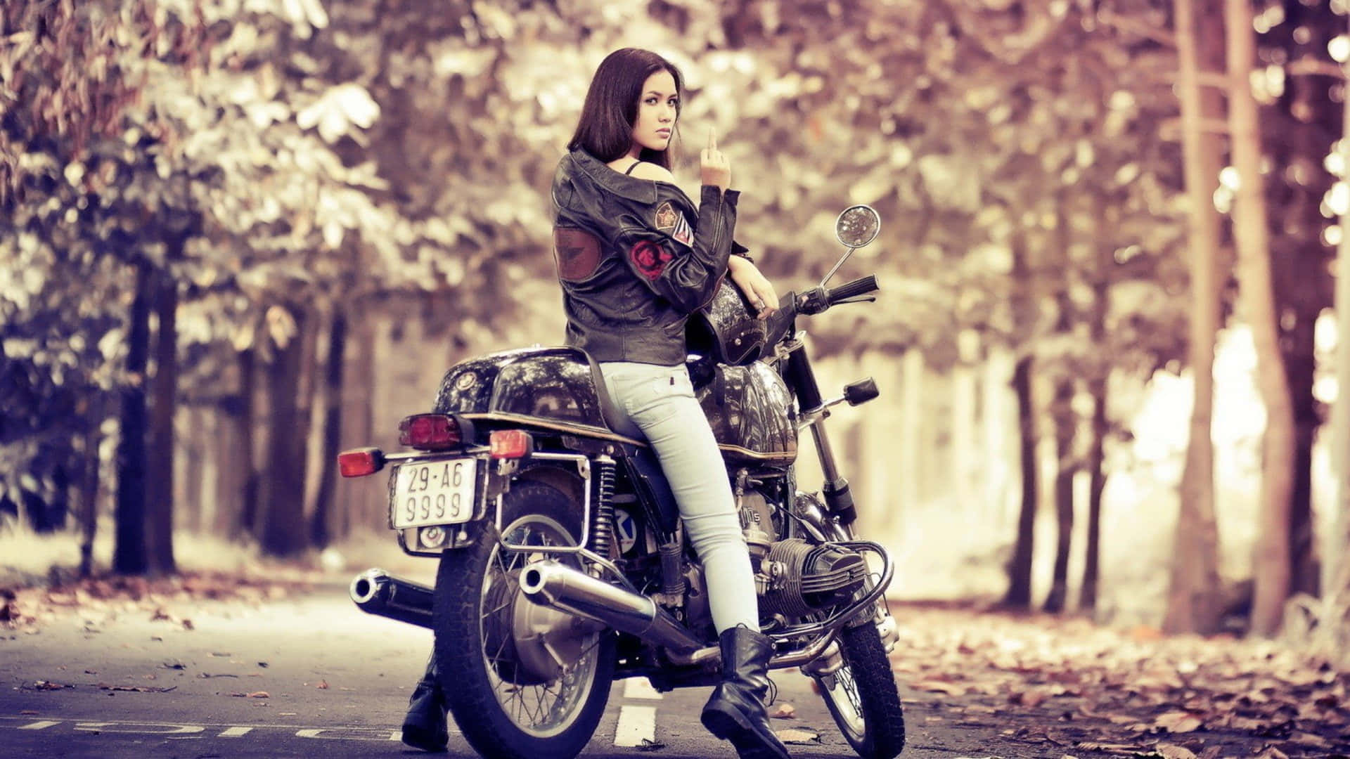 A Woman Sitting On A Motorcycle In The Woods Background