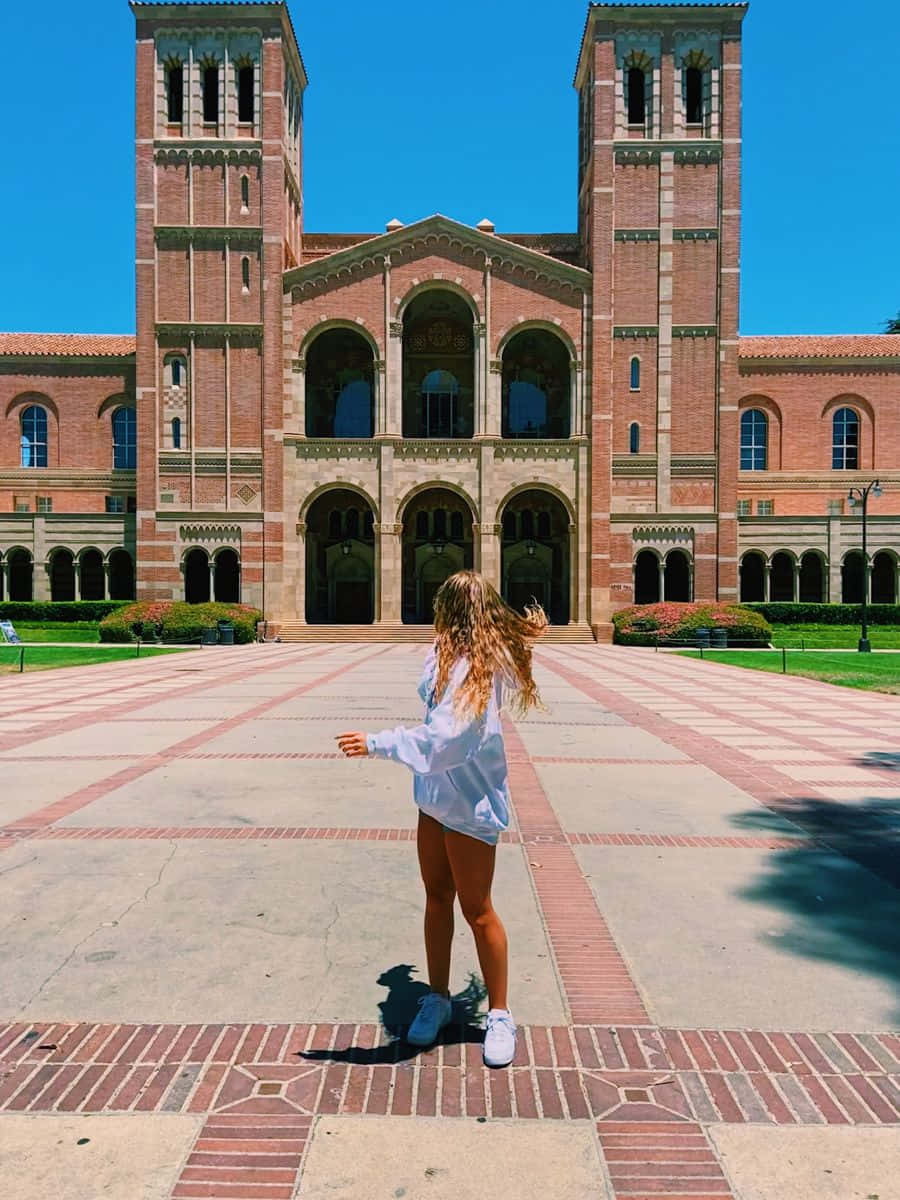 A Woman Standing In Front Of A Large Building Background