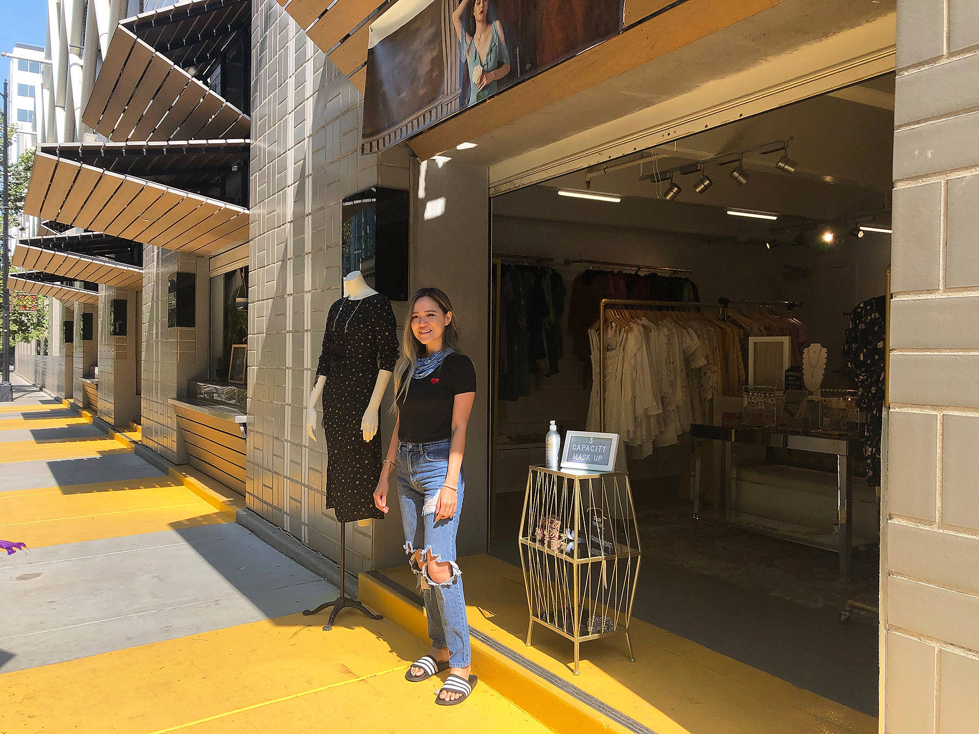 A Woman Standing In Front Of A Store With Clothes On Display