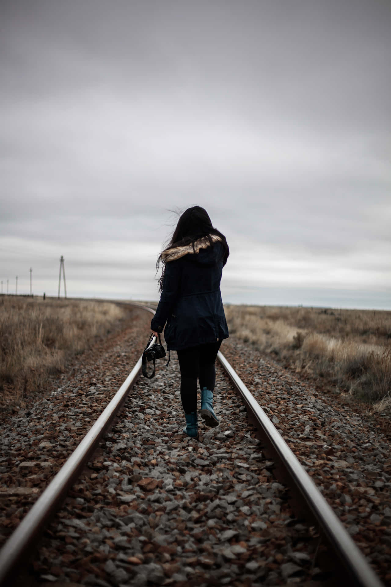 A Woman Walking On Train Tracks Background