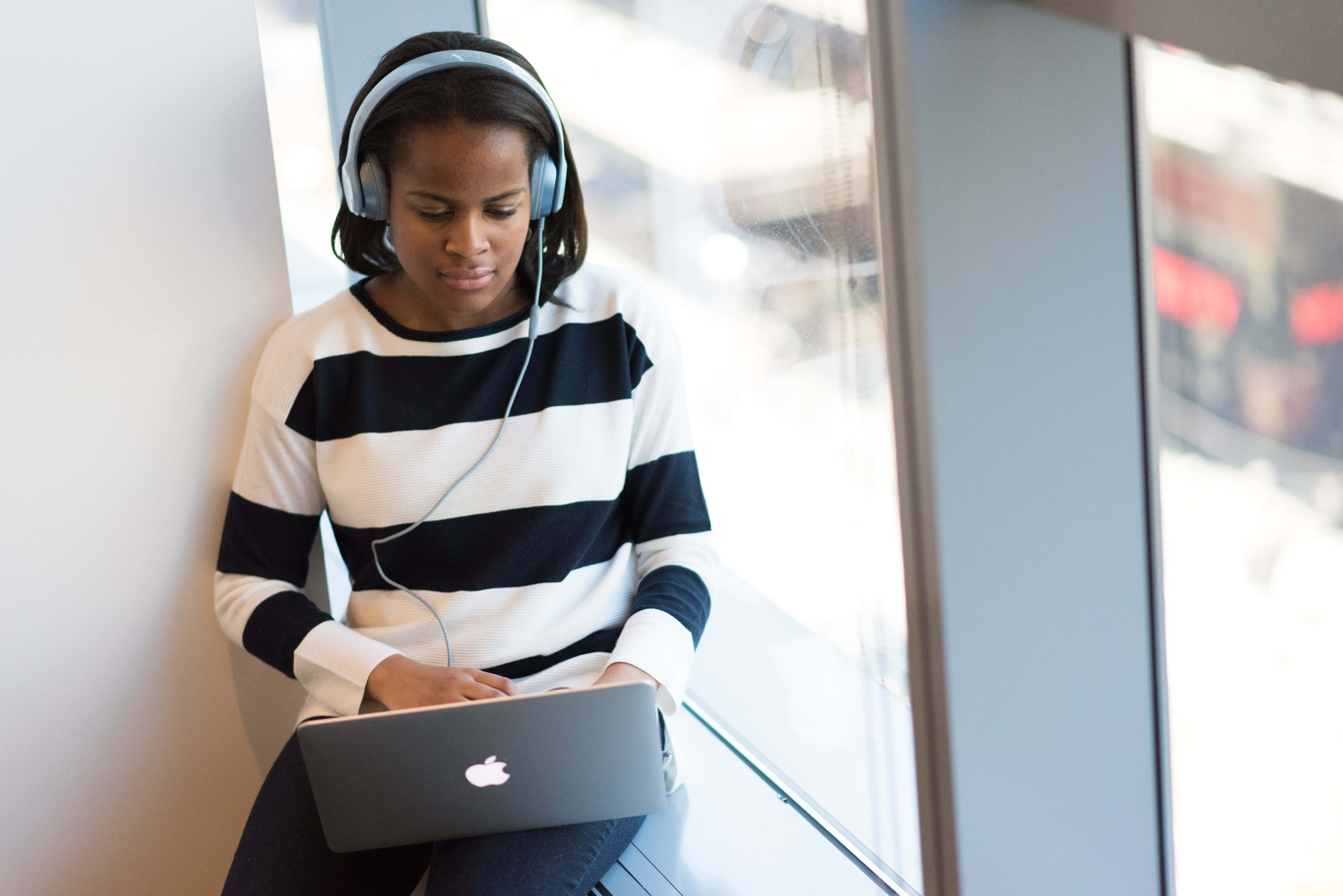 A Woman Wearing Headphones And Using A Laptop Background