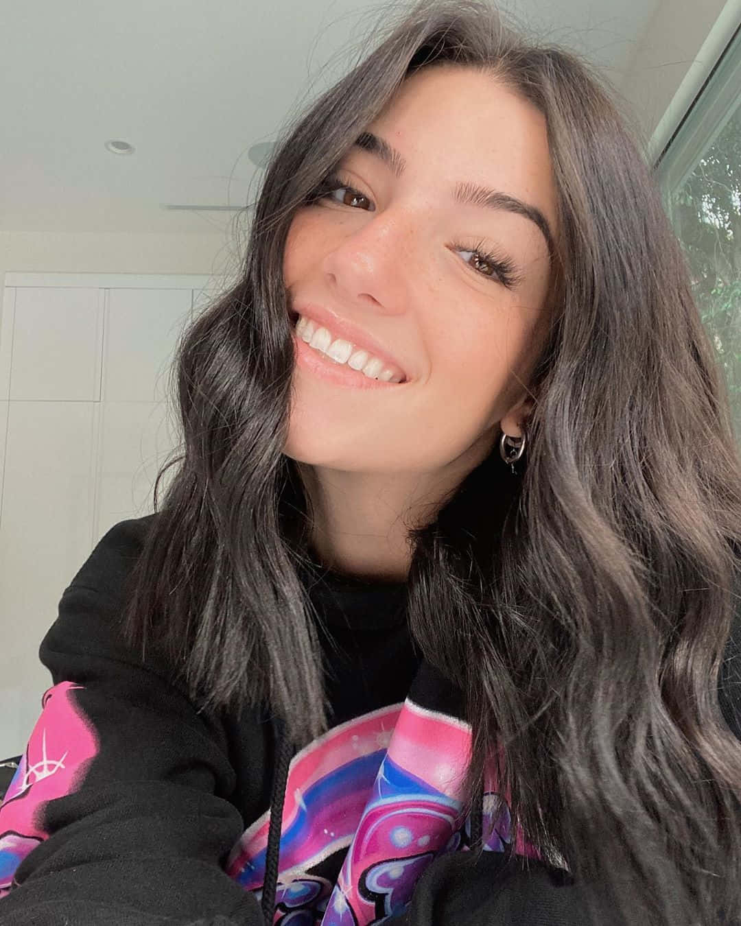 A Woman With Long Hair And A Black Sweatshirt Smiling