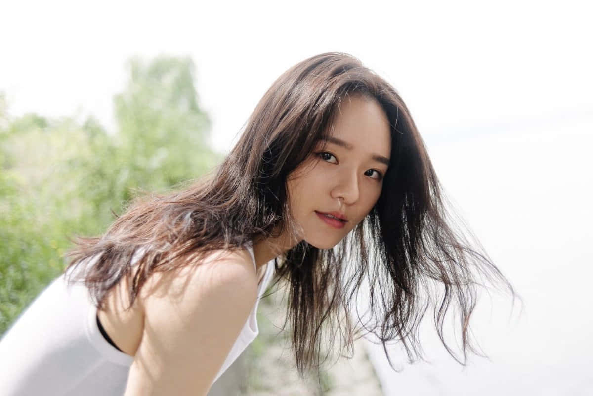 A Woman With Long Hair Posing By The Water Background