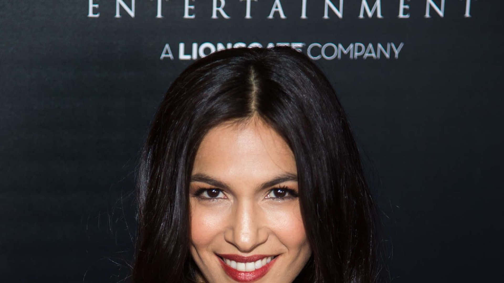 A Woman With Long Hair Smiling At The Red Carpet Background