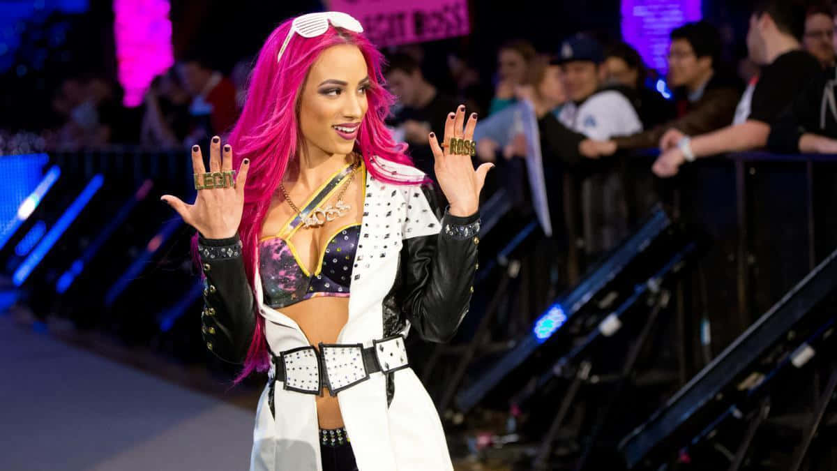 A Woman With Pink Hair And Black Outfit Is Standing On A Stage