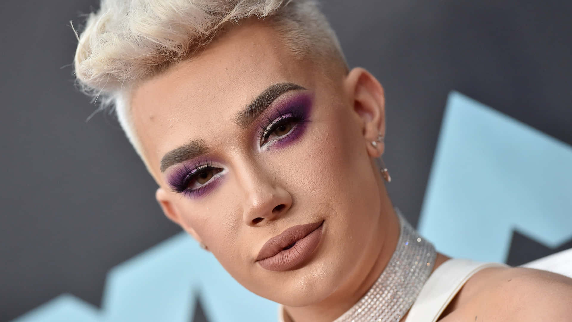 A Woman With Purple Makeup And A White Shirt Background