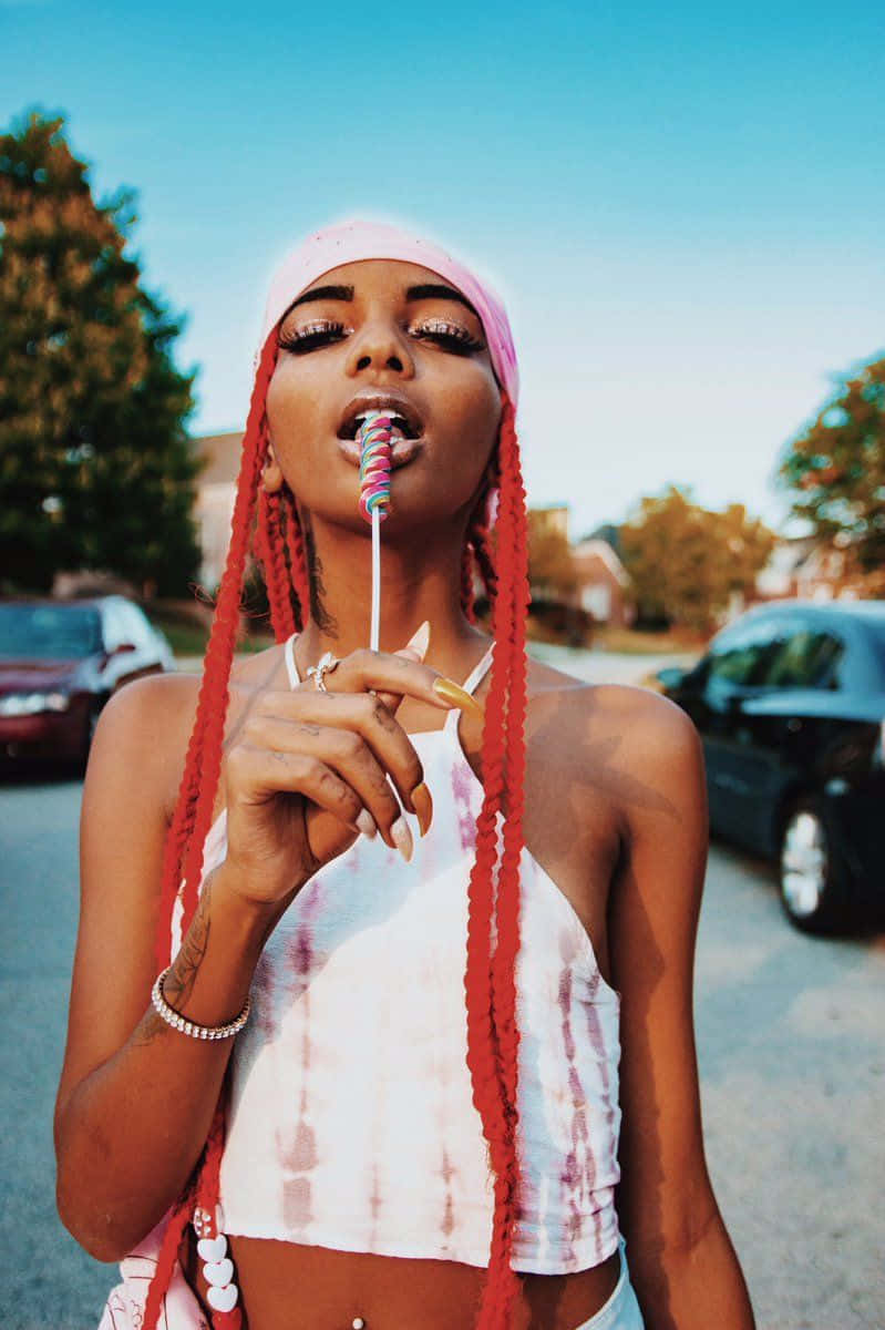 A Woman With Red Dreadlocks Is Holding A Lollipop Background