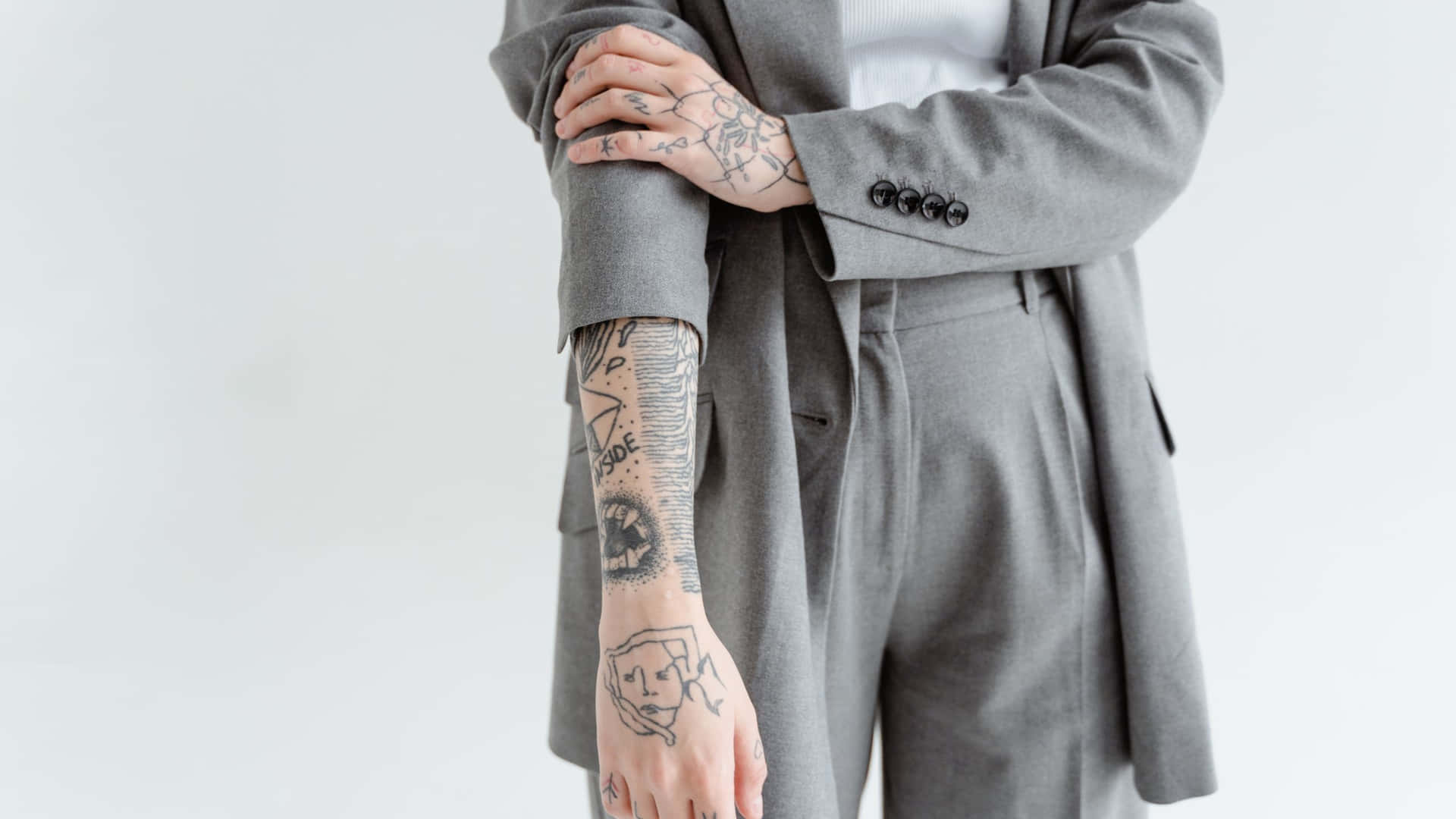 A Woman With Tattoos Wearing A Grey Suit Background