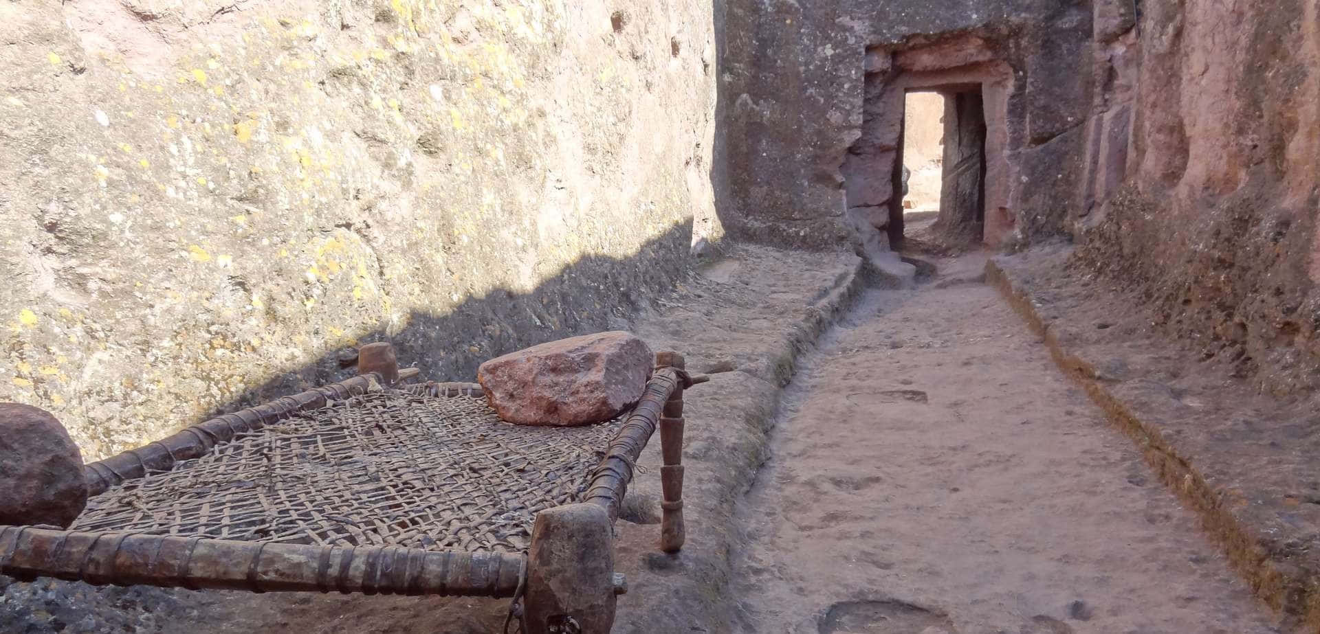 A Wooden Bed Frame Beside Lalibela's Rock-hewn Church Background