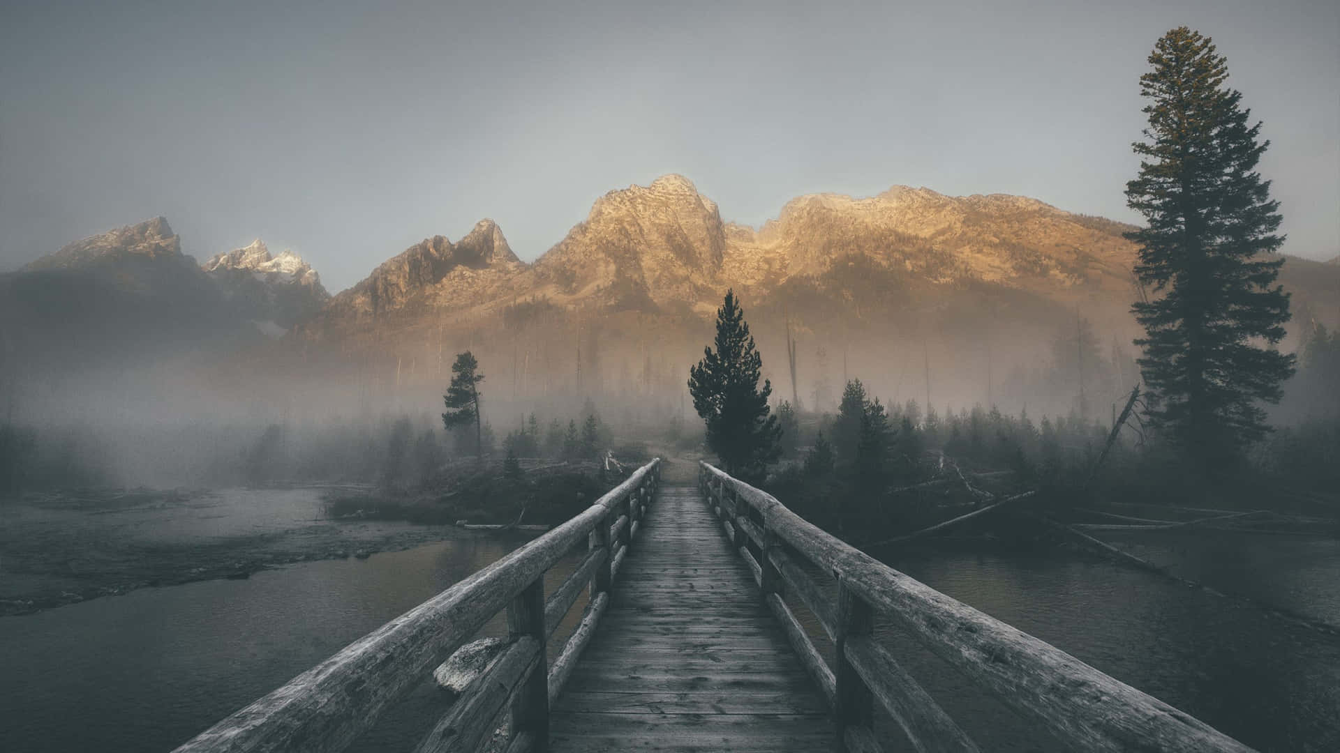 A Wooden Bridge Over A River In The Mountains