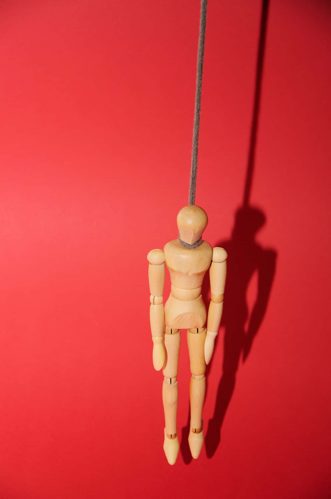A Wooden Mannequin Hanging From A String