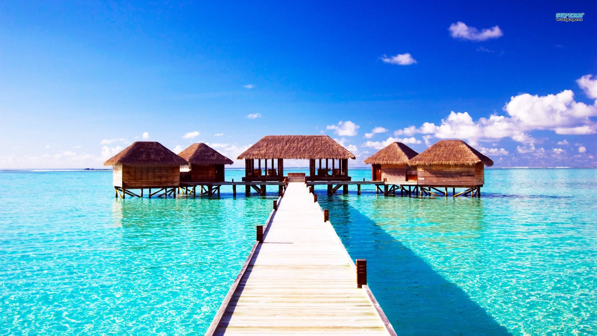 A Wooden Pier With Huts On It Background