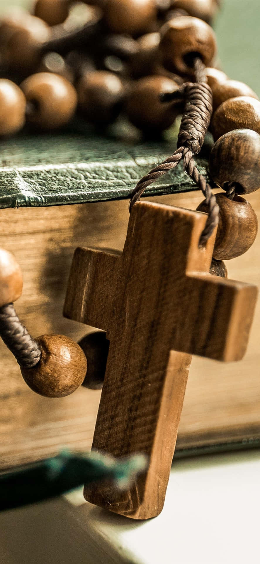 A Wooden Rosary Is Sitting On Top Of A Book Background