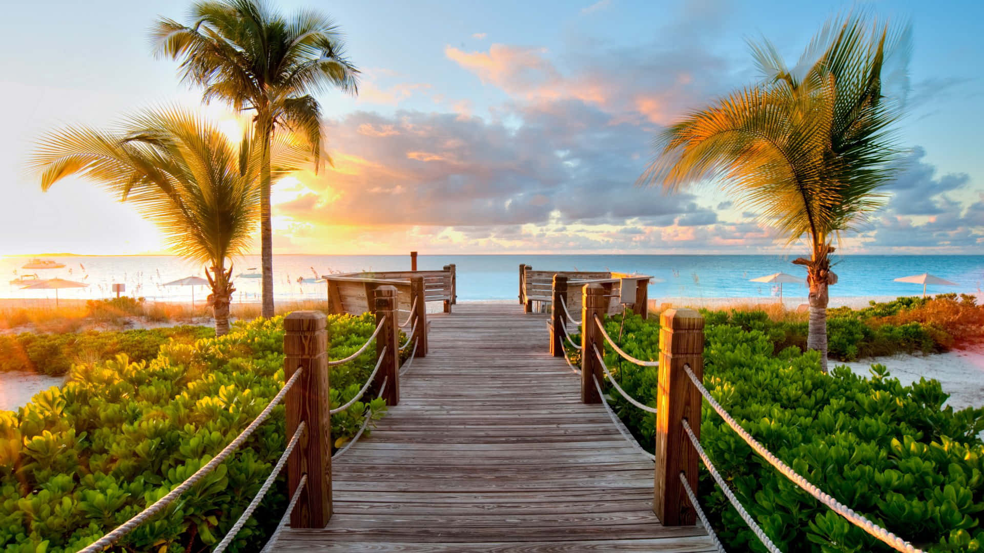 A Wooden Walkway Leading To The Beach At Sunset