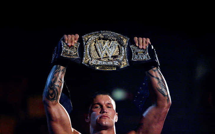 A Wrestler Holding Up A Wwe Championship Belt Background