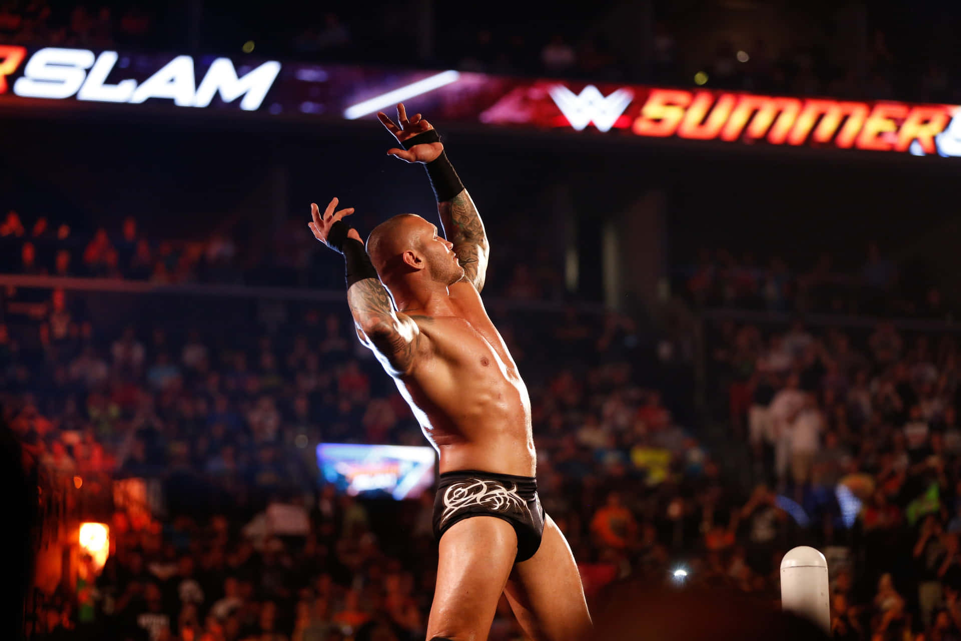 A Wrestler Is Standing In The Ring With His Arms Raised Background