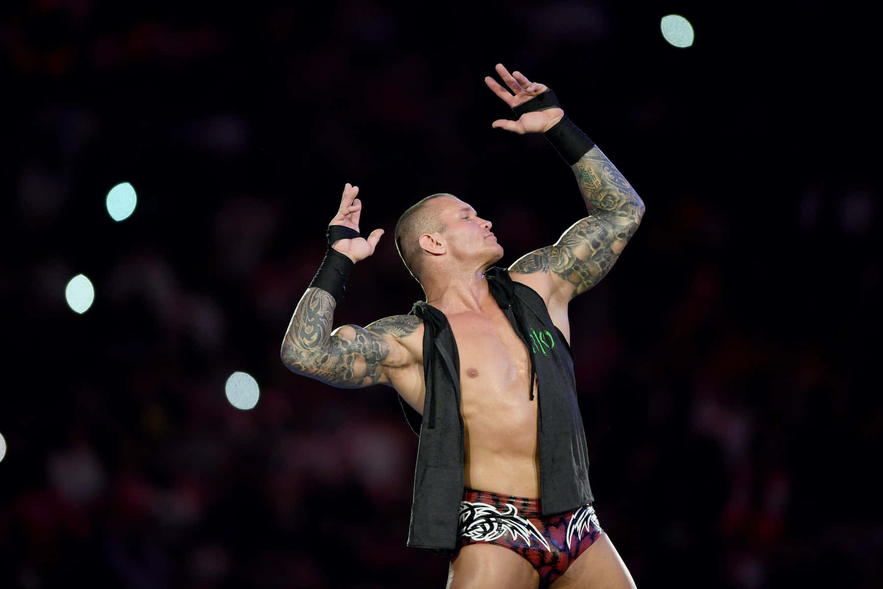 A Wrestler With Tattoos Is Holding His Arms Up Background