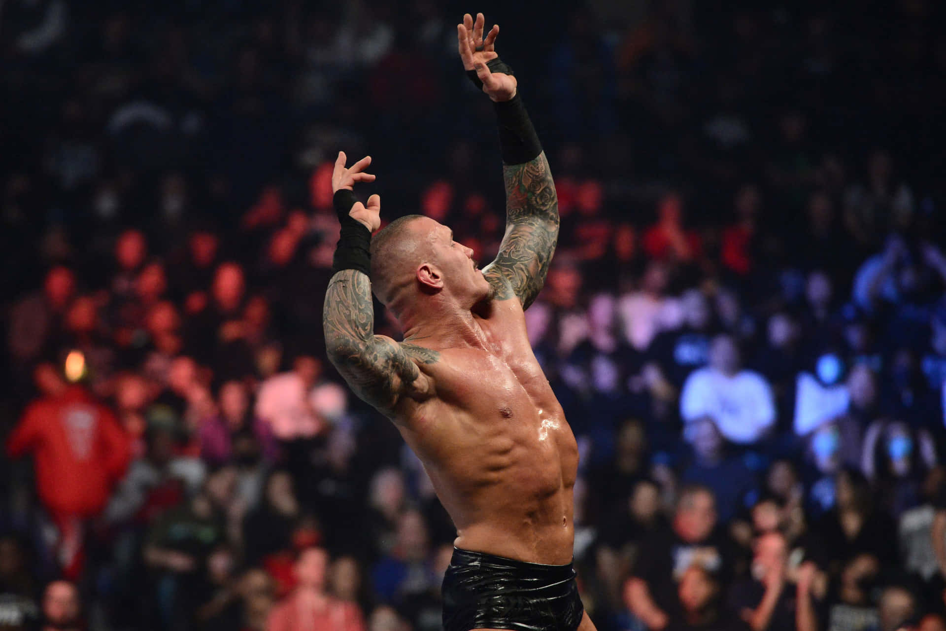 A Wrestler With Tattoos Is Holding His Arms Up In The Air Background