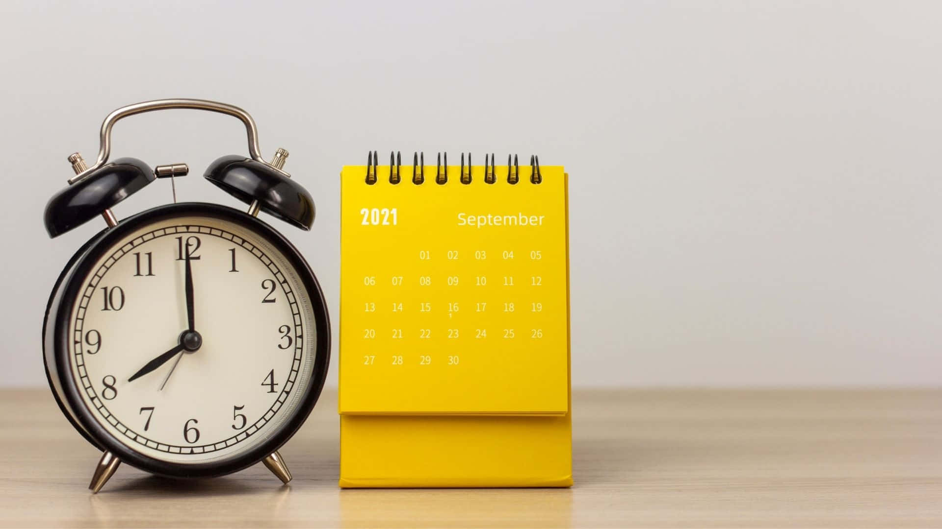 A Yellow Alarm Clock Next To A Calendar Background