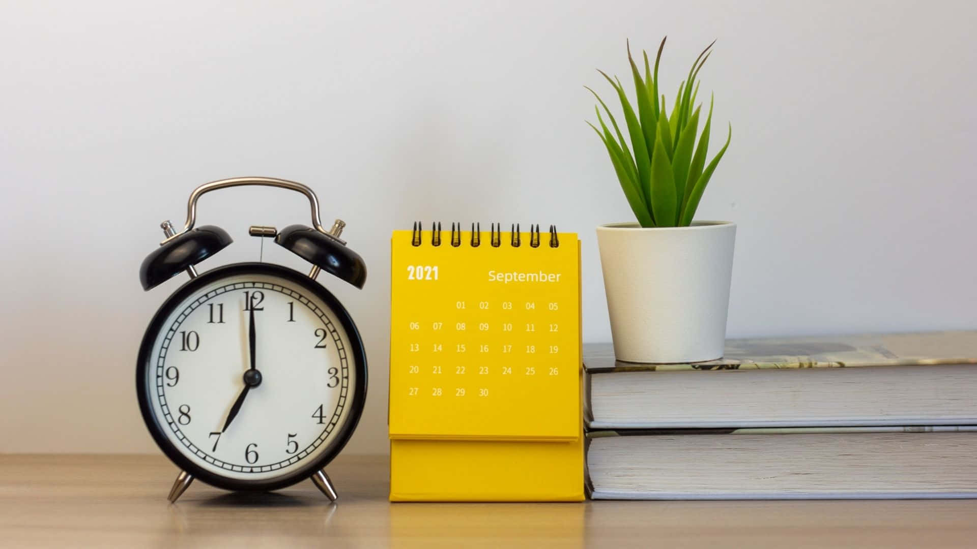 A Yellow Alarm Clock Sits Next To A Book And Plant