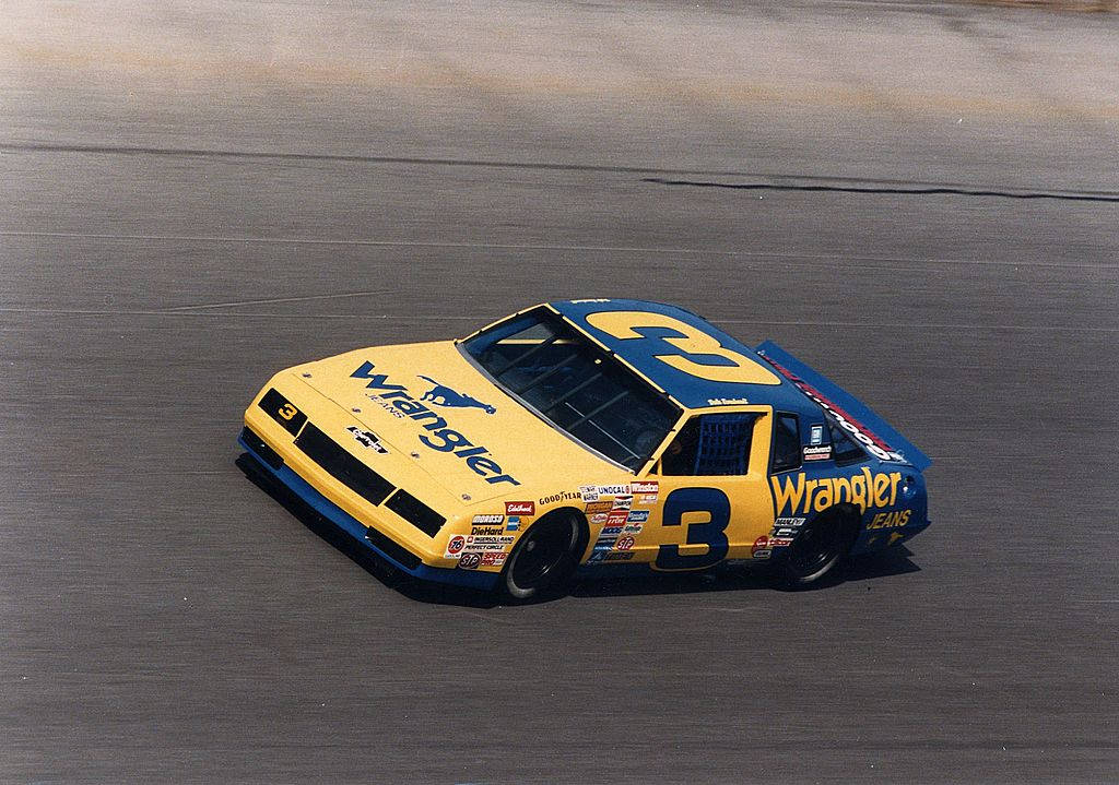 A Yellow And Blue Nascar Car Driving On A Track Background