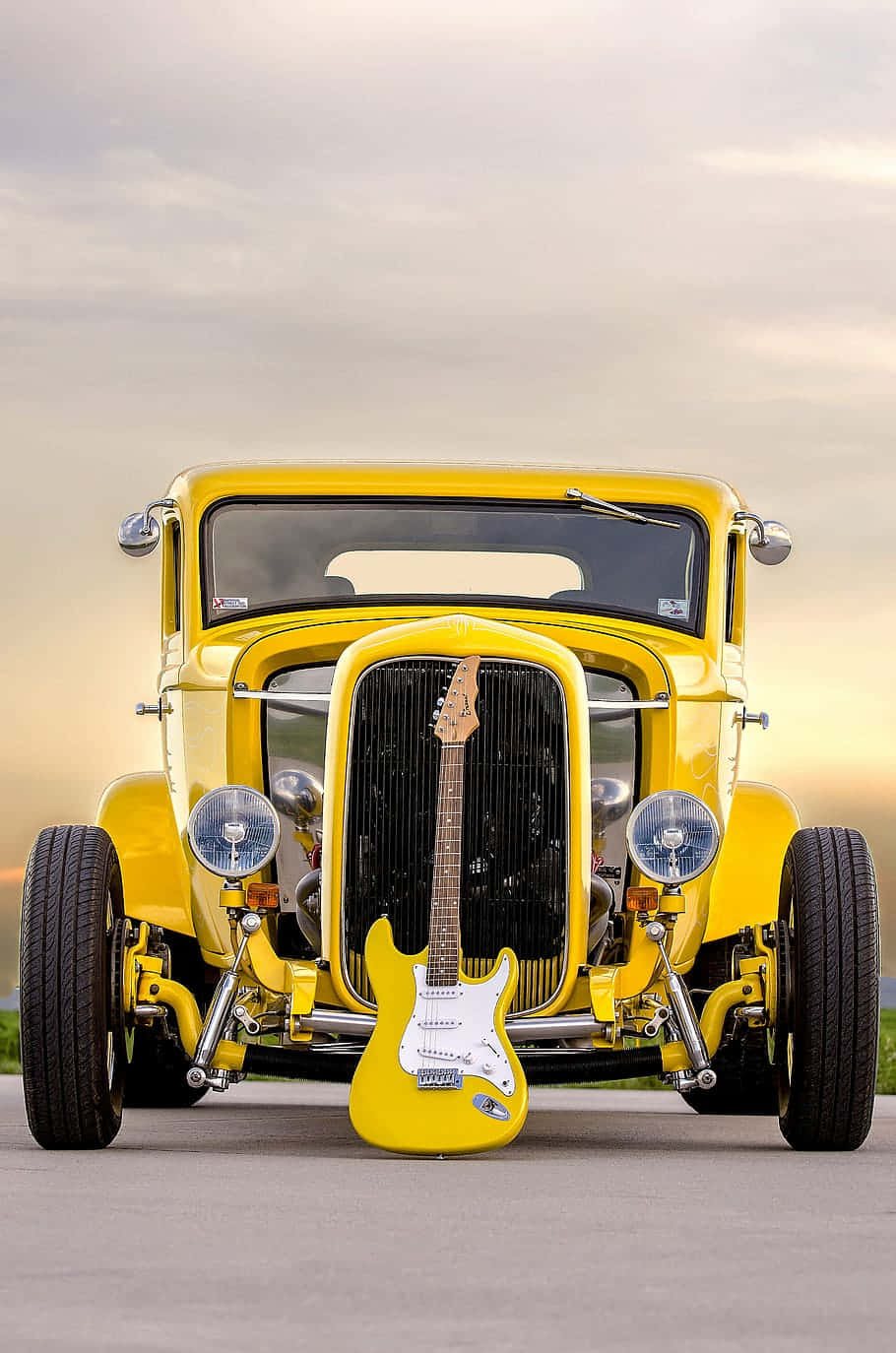 A Yellow Car With A Guitar In Front Of It Background