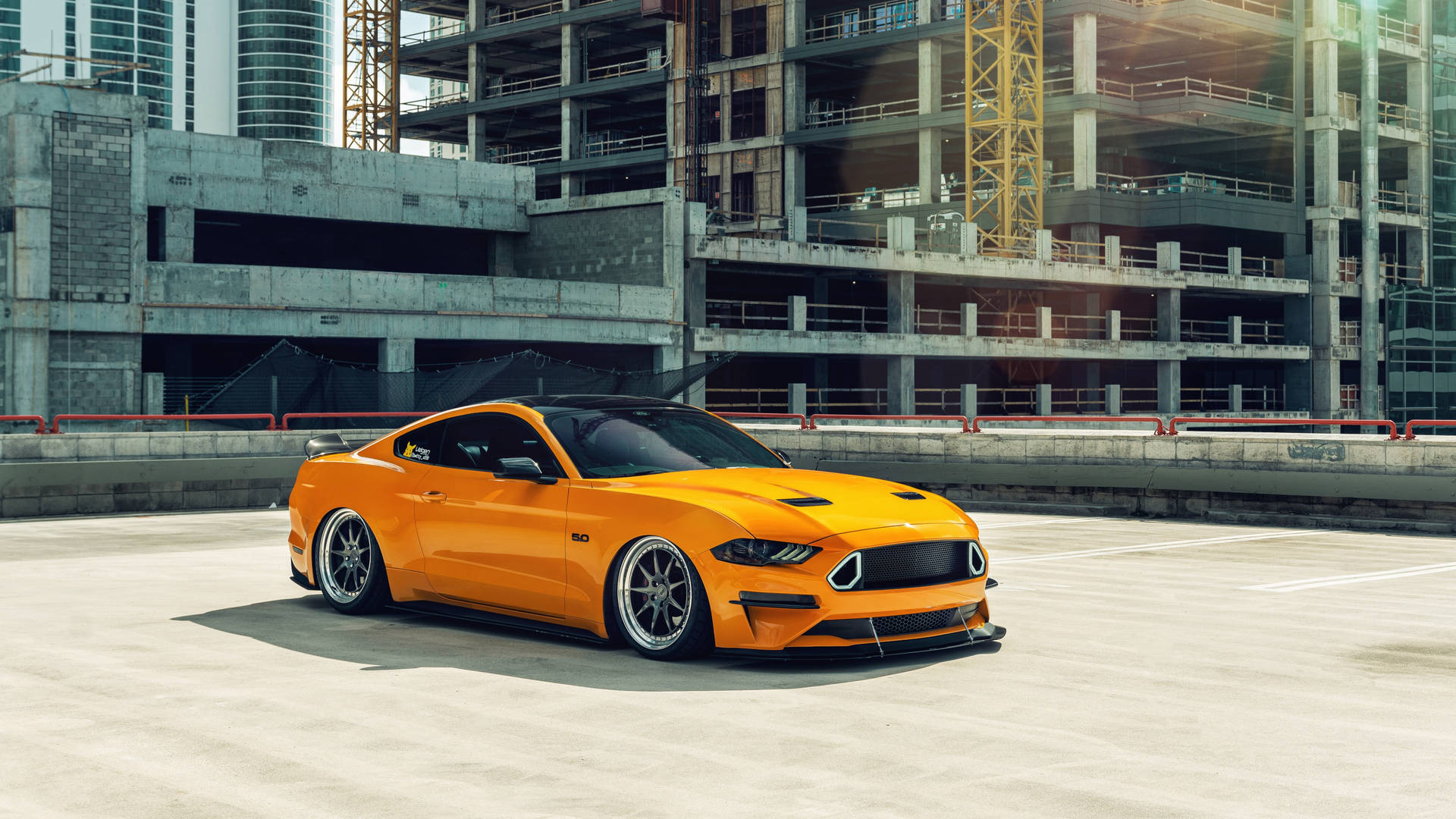 A Yellow Ford Mustang Parked In Front Of A Building Background