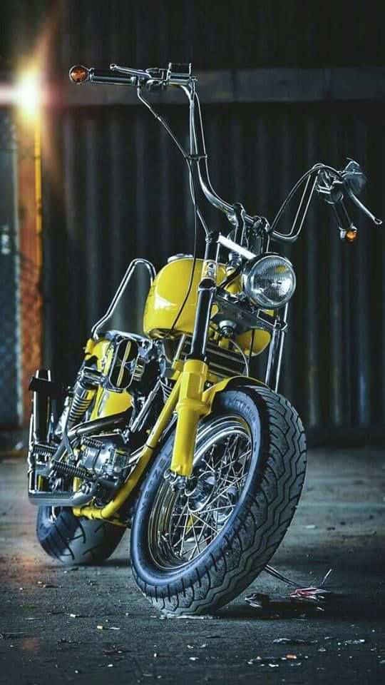 A Yellow Motorcycle Parked In A Dark Garage Background