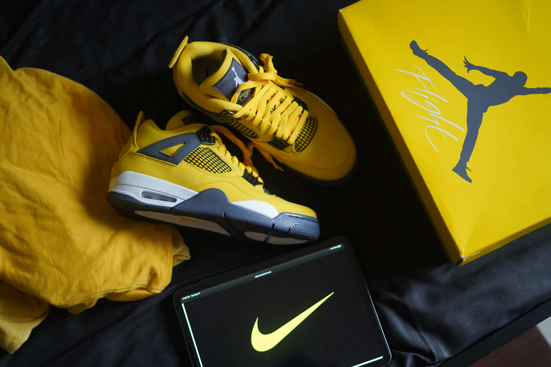 A Yellow Nike Air Jordan 4 Is Sitting On A Bed Background