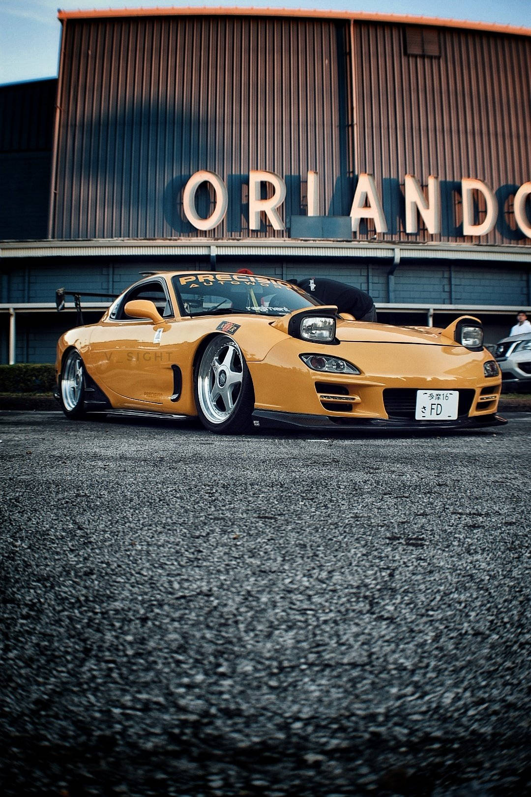 A Yellow Sports Car Parked In Front Of A Building Background