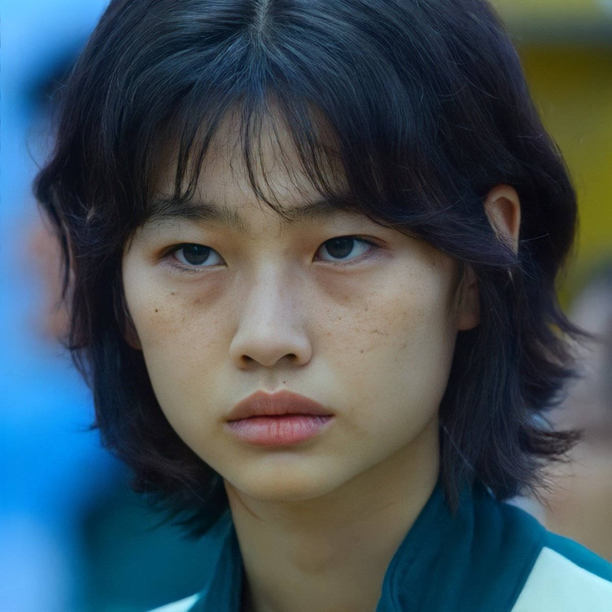 A Young Asian Girl With Dark Hair And A Green Jacket