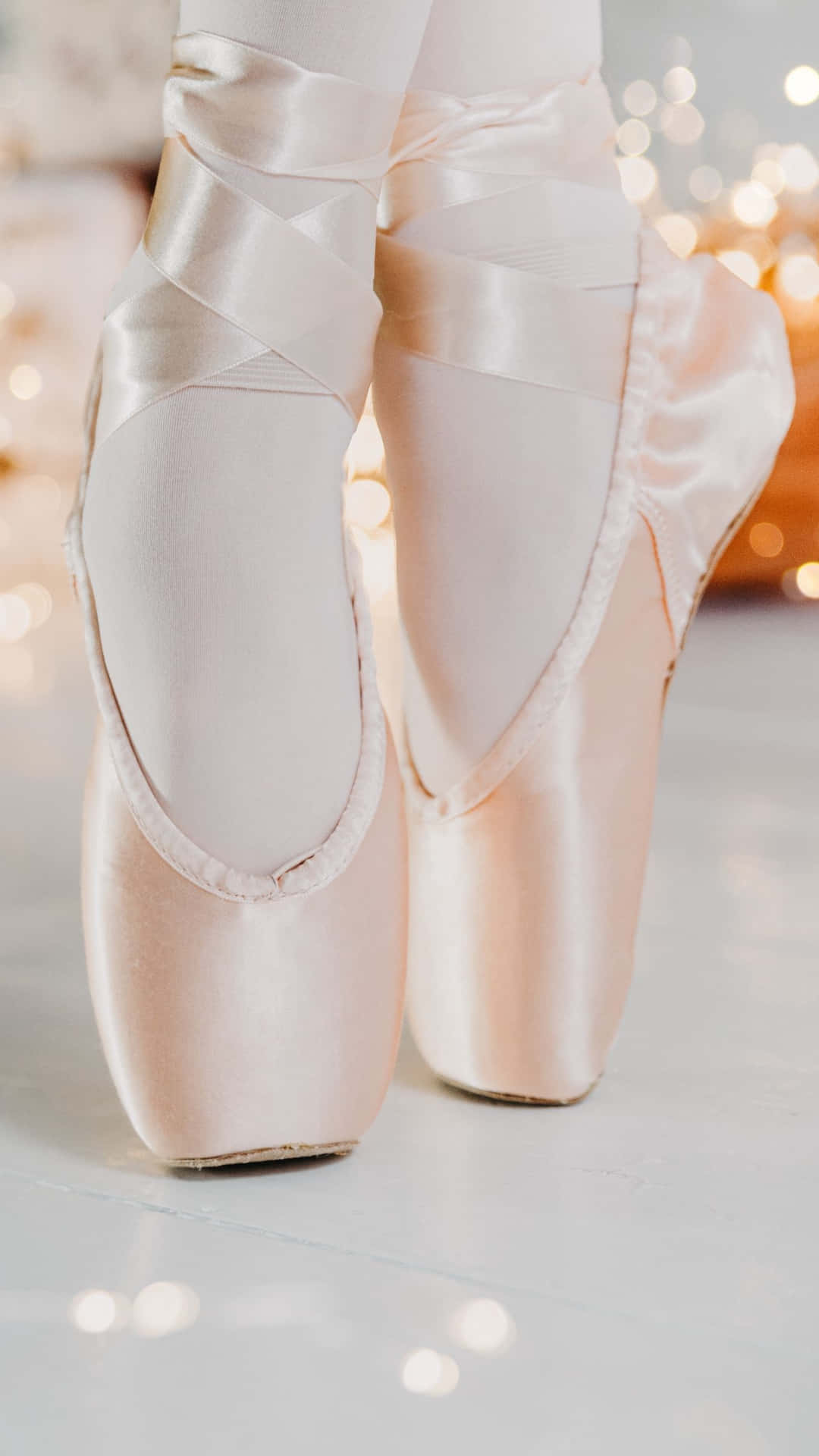 A Young Ballerina Wearing Classic Pointe Shoes Gracefully In A Tutu Background