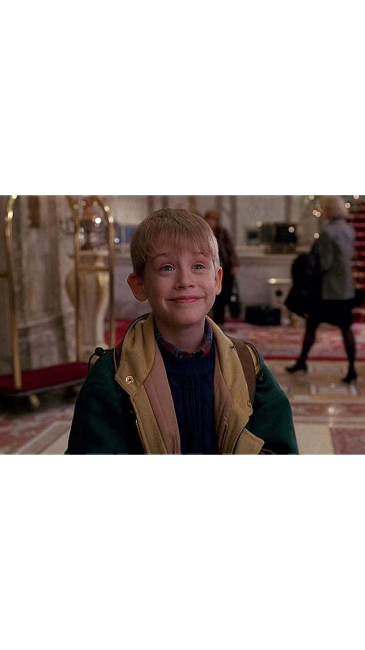 A Young Boy In A Green Jacket Is Smiling Background