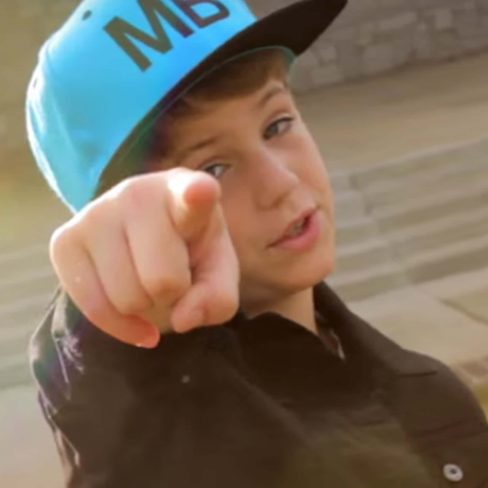 A Young Boy Pointing At Something With A Hat On Background