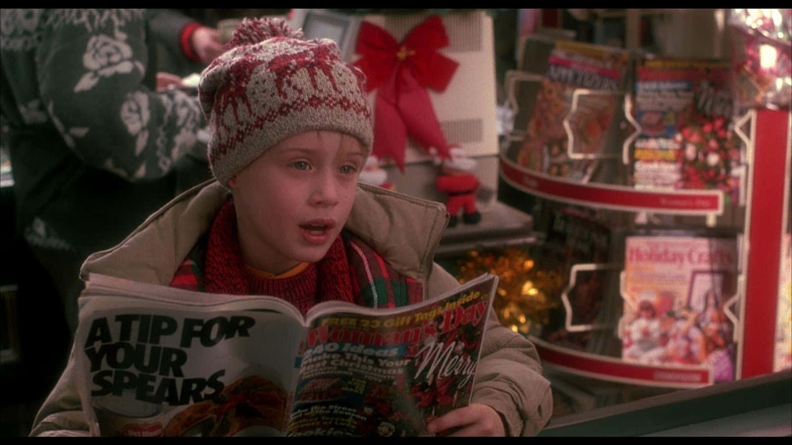 A Young Boy Reading A Christmas Magazine In A Store Background