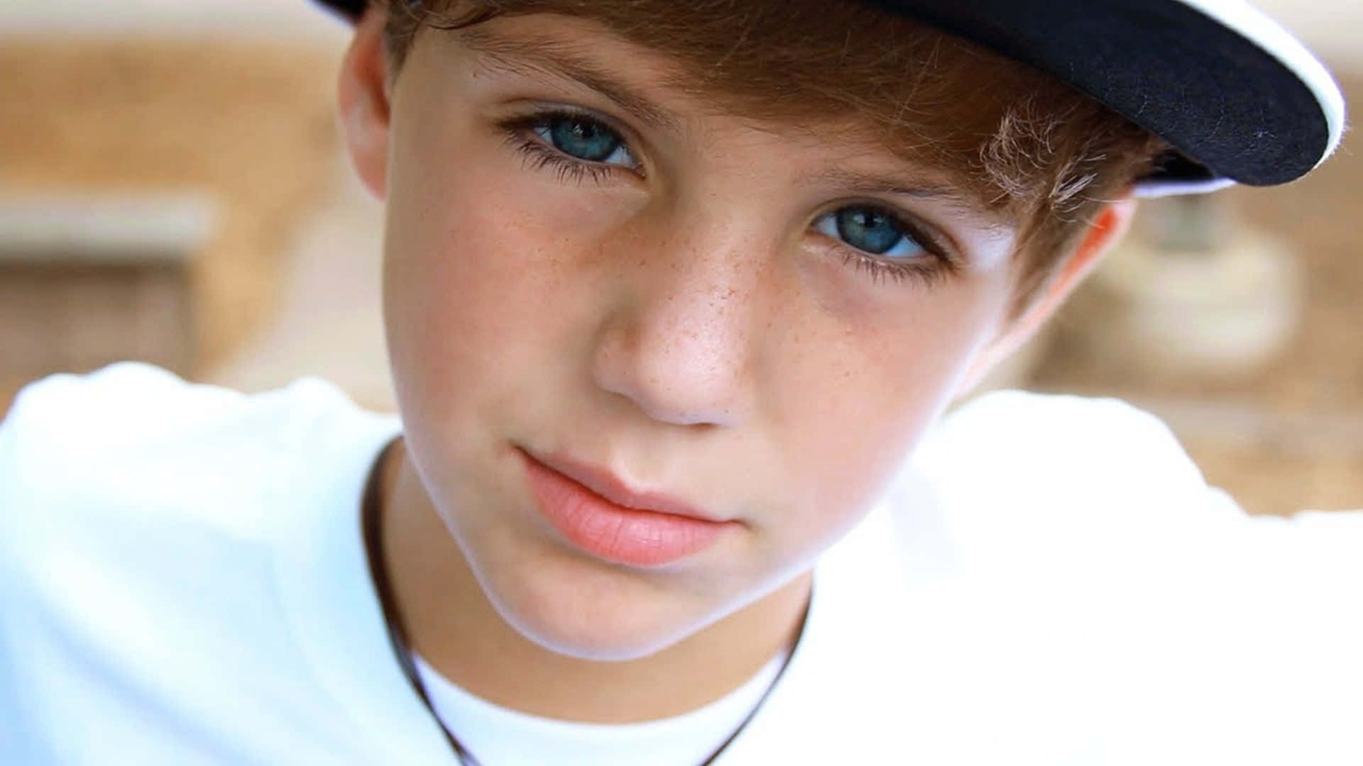 A Young Boy Wearing A Baseball Cap And A Necklace Background