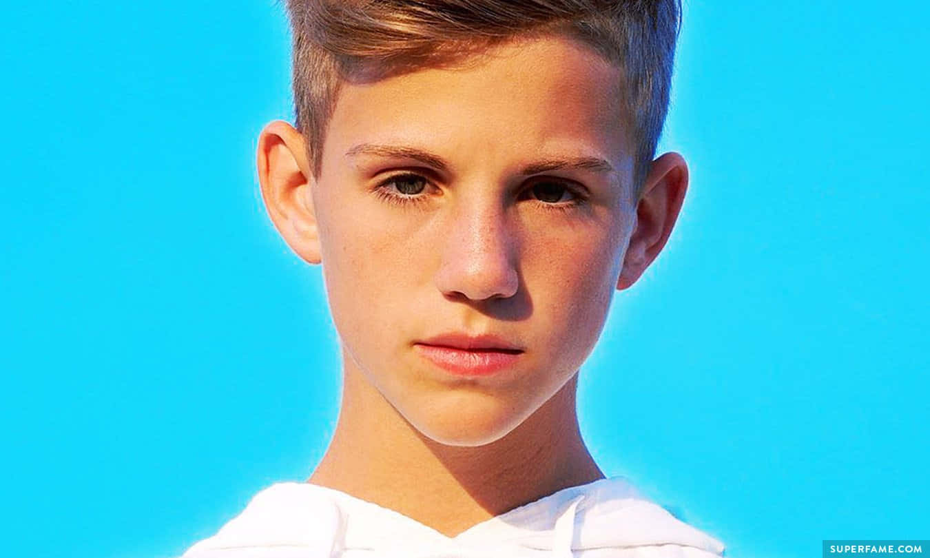 A Young Boy With A Short Haircut Is Looking At The Camera Background