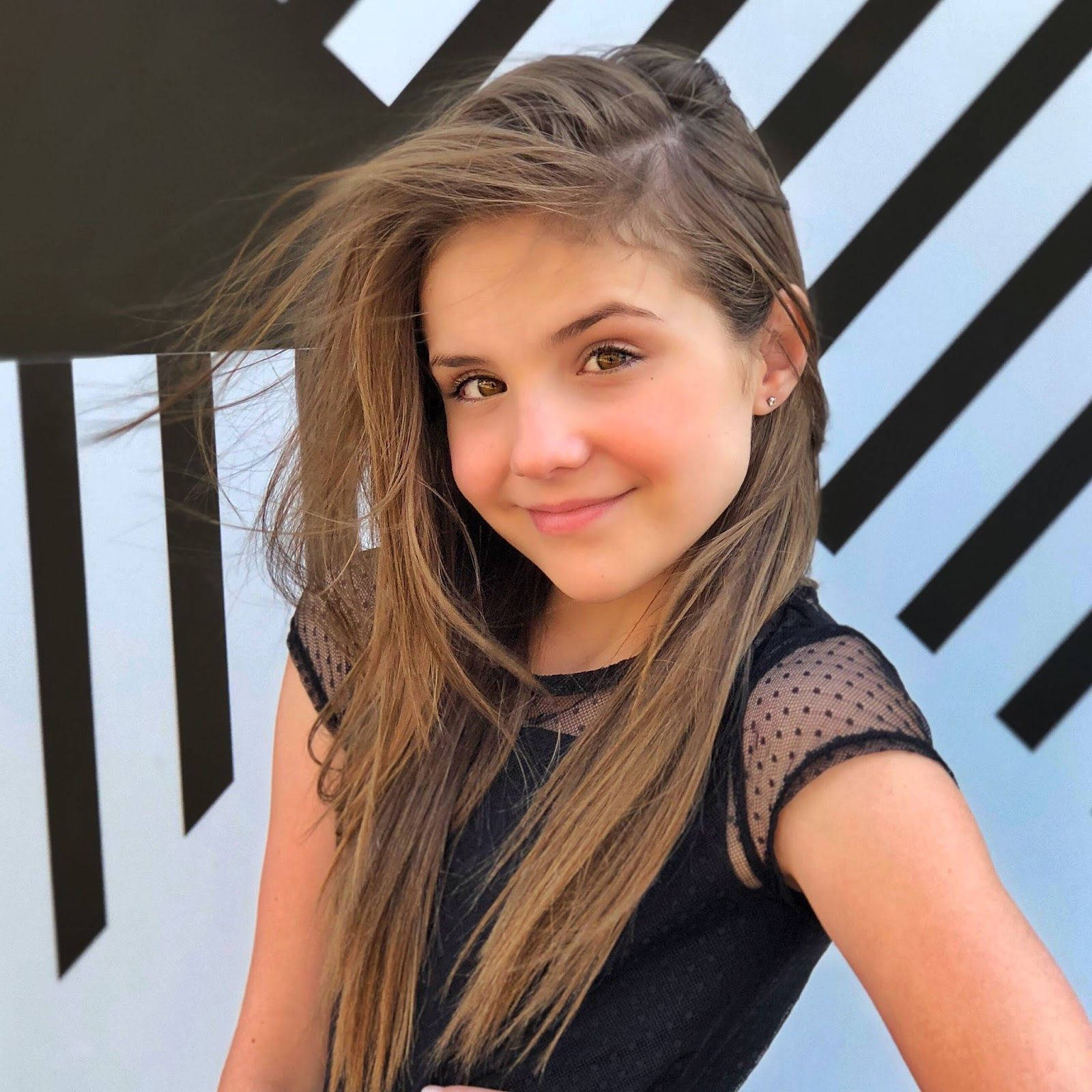 A Young Girl In A Black Dress Posing For A Photo Background