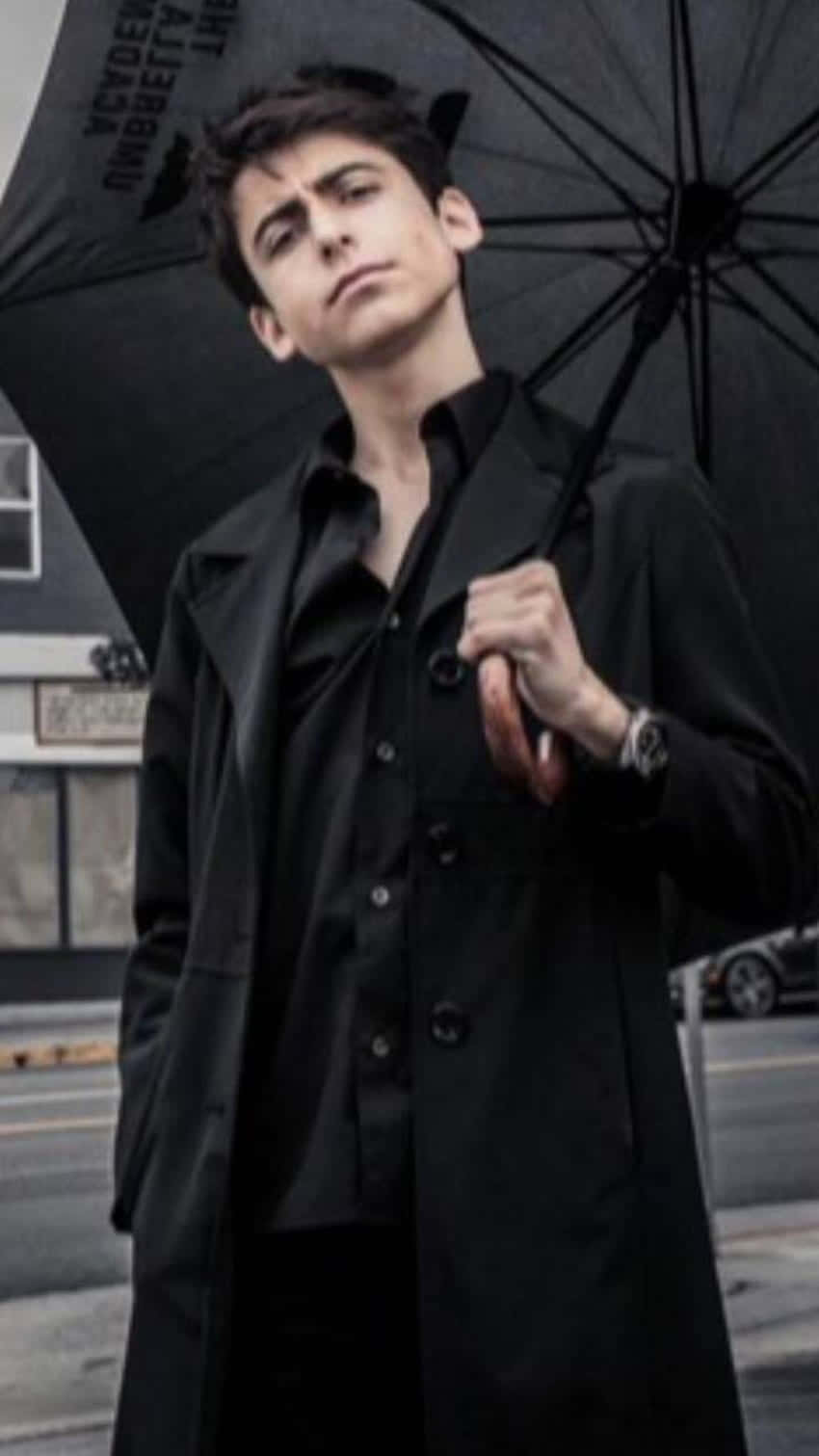 A Young Man Holding An Umbrella On The Street Background