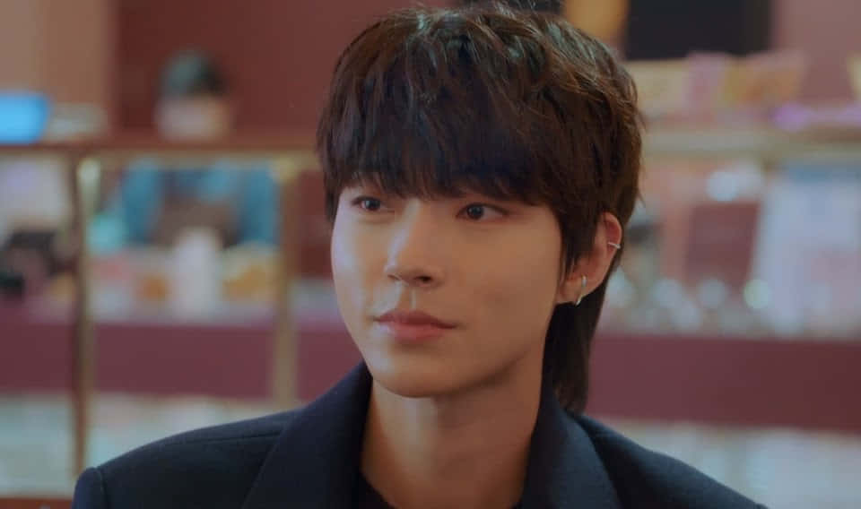 A Young Man In A Black Jacket Is Looking At Something Background