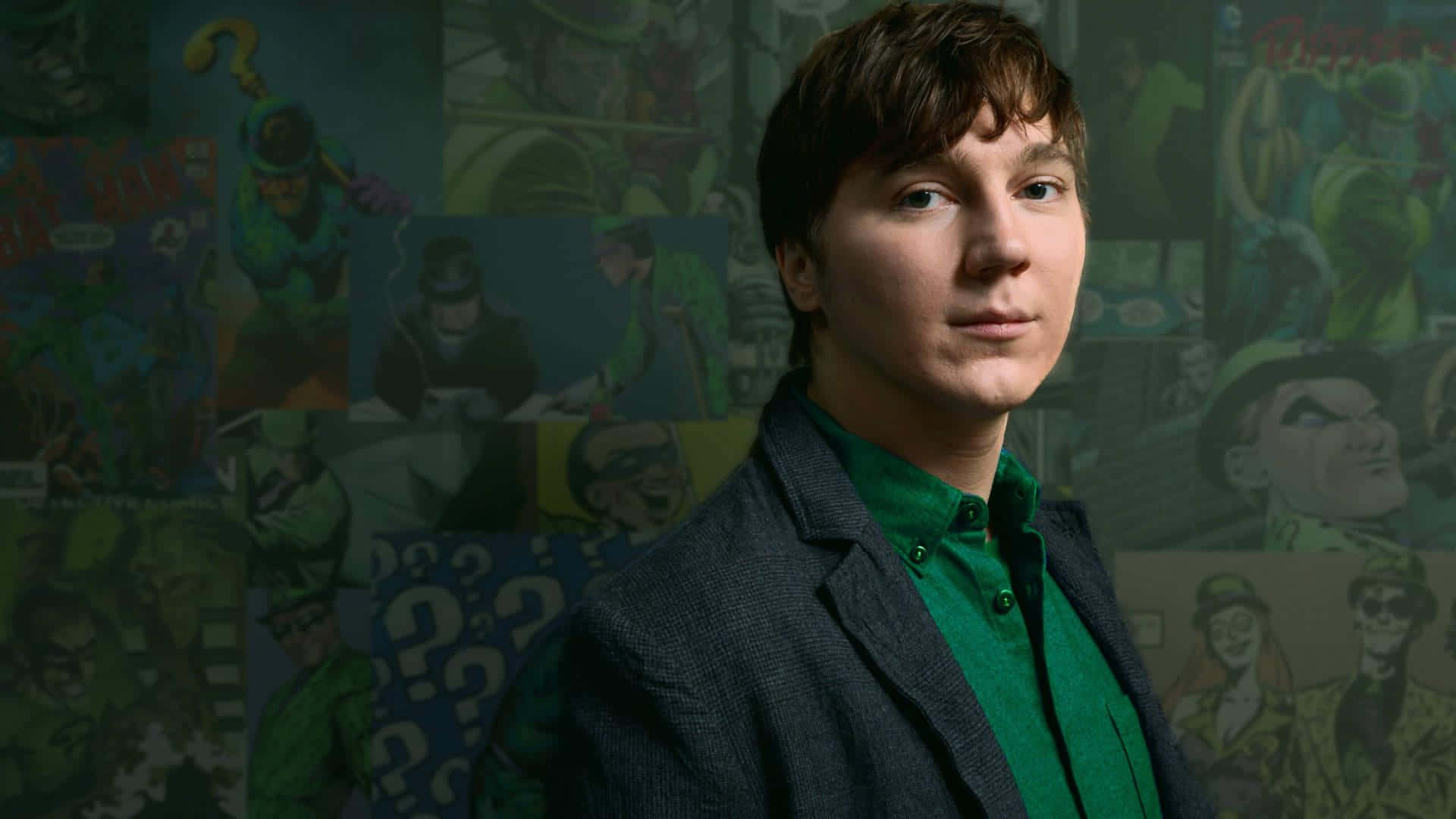 A Young Man In A Green Jacket Standing In Front Of A Wall Of Comics Background