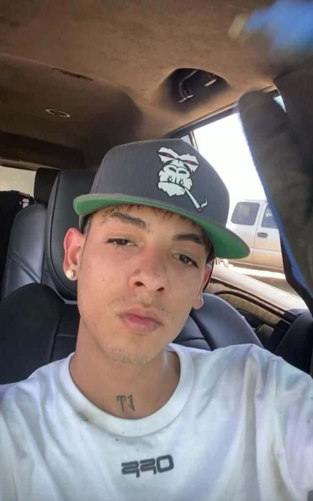 A Young Man In A Hat Is Sitting In A Car Background
