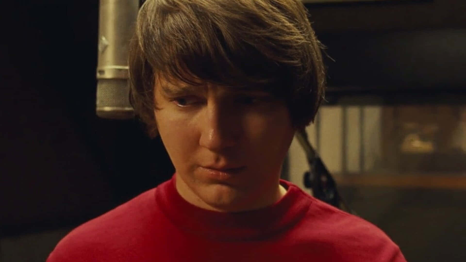 A Young Man In A Red Shirt Is Standing In Front Of A Microphone Background