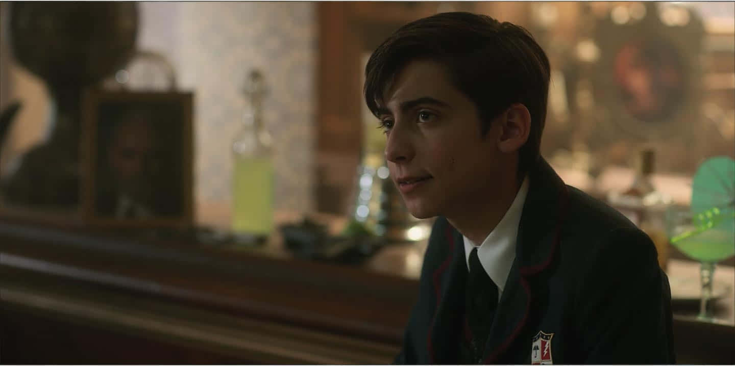 A Young Man In A School Uniform Sitting At A Bar Background