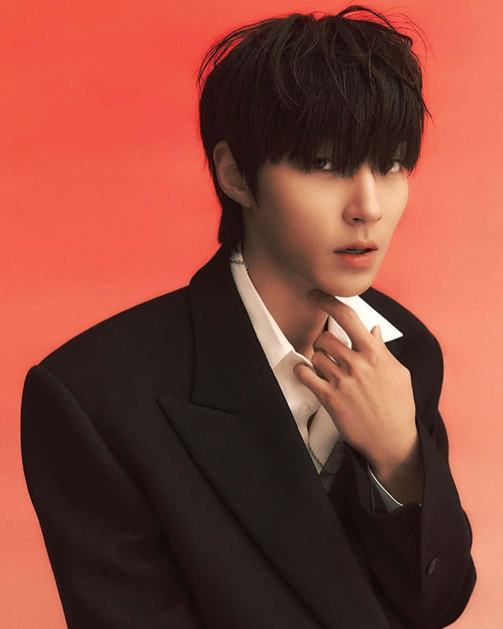 A Young Man In A Suit Posing With His Hand On His Chin Background