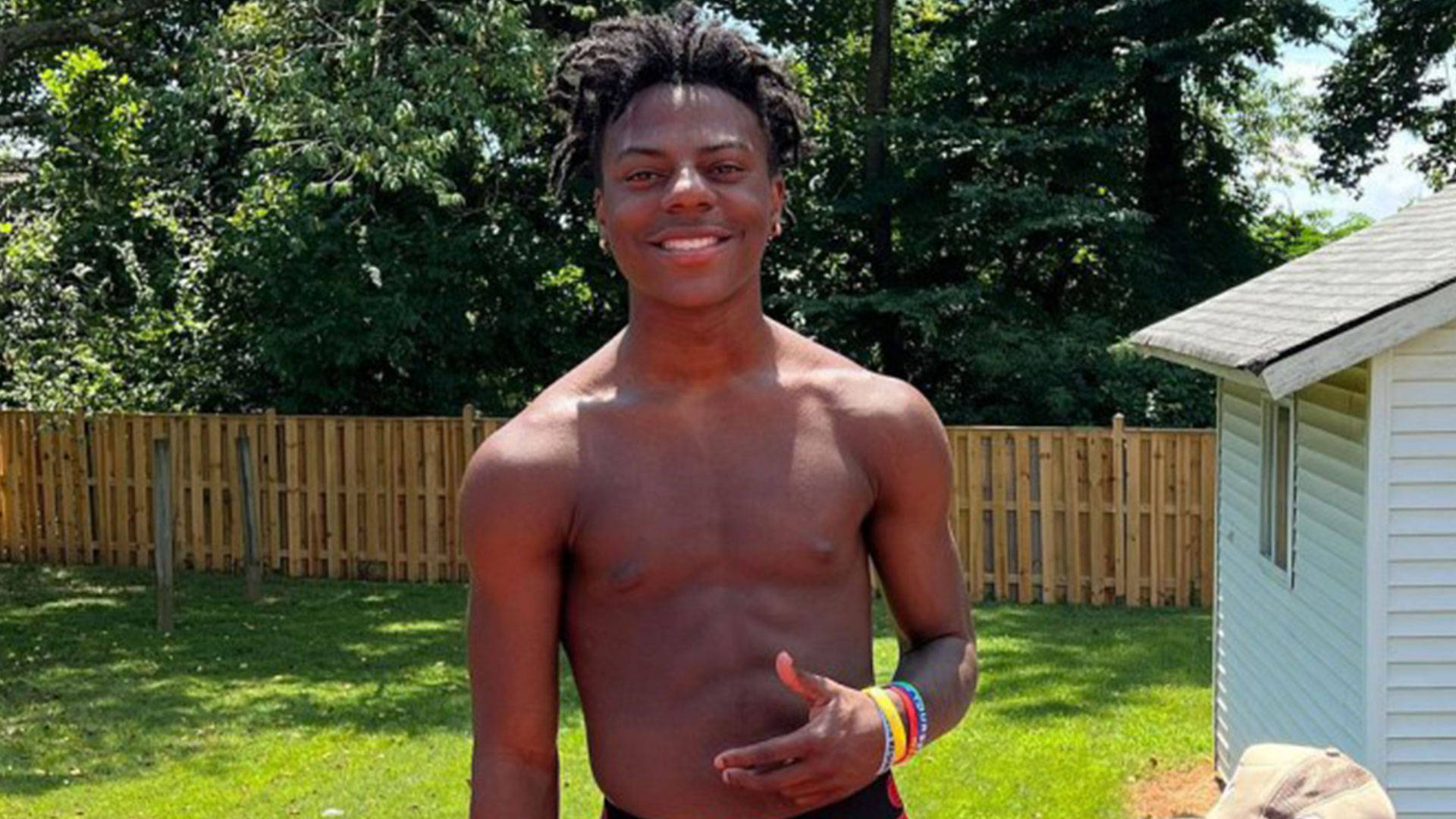 A Young Man In A Swimsuit Standing In A Yard Background